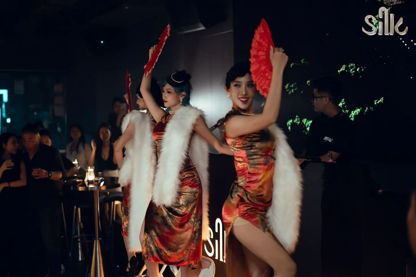 Traditional Vietnamese fan dancers performing in red and gold dresses during themed cultural night